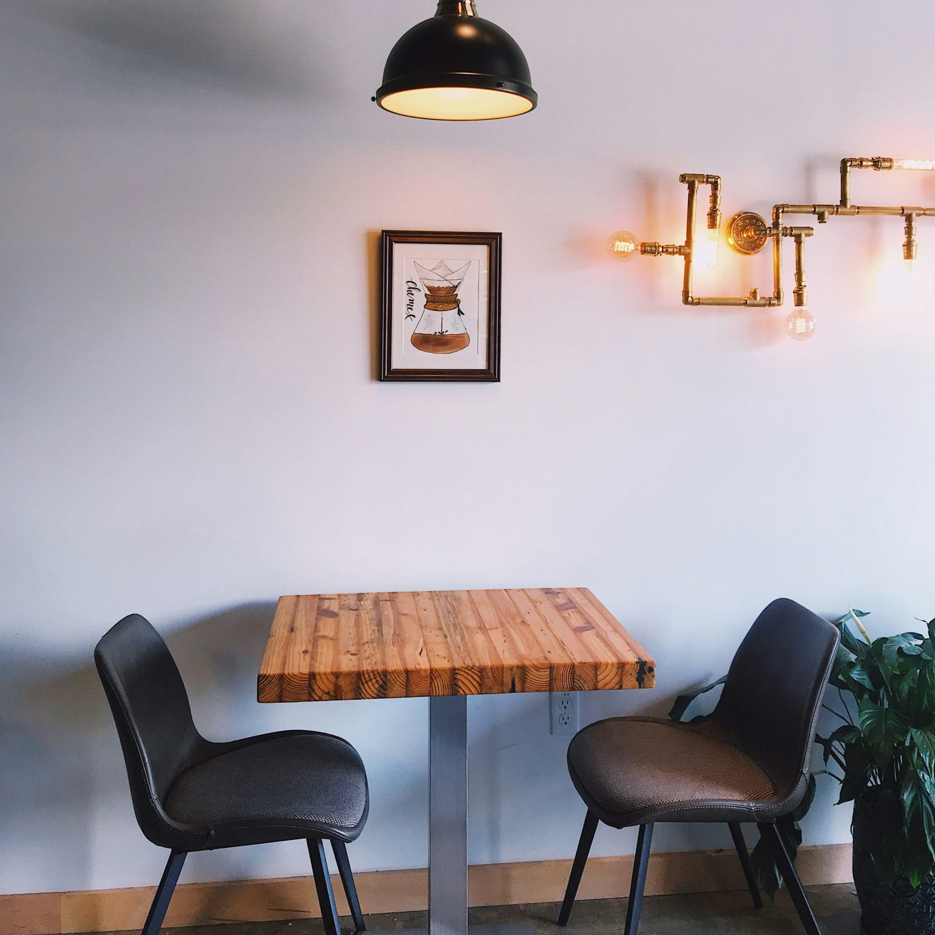 A small wooden table with two chairs in a warmly lit café setting, creating an intimate and inviting atmosphere.